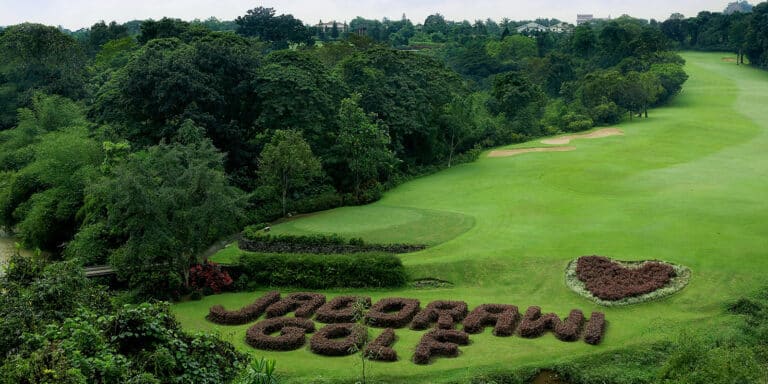 Old course 1 - a lush, green golf course surrounded by dense trees, with JAGORAWI GOLF and a heart shape spelt out in trimmed bushes near the foreground of this scenic golf club.